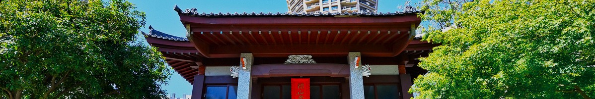 Snapshot of the top portion of a shrine surrounded on both sides by large trees.