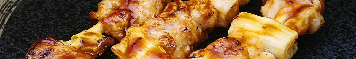 Close-up image of browned chicken and onion skewers, three on a plate.