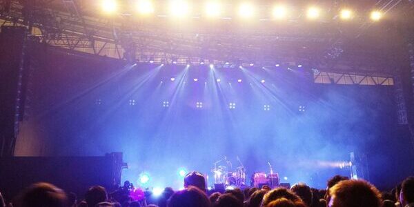 image of a live music venue stage with lights shining down from the ceiling onto the instruments, and the crowd below