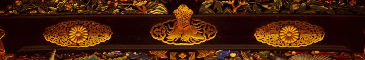 Gold leaf artwork on a temple banister depicting intricate flowers in oval motifs.