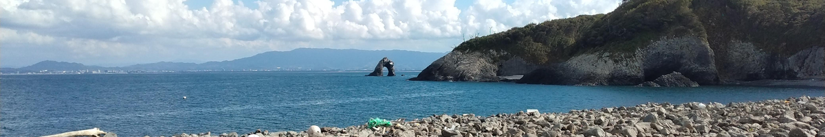 Panoramic view of a large body of water with an arched rock jutting out in the middle of the water, and a larger delta to the right of the arched rock.